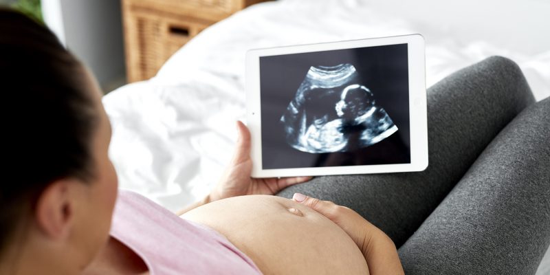 Pregnant woman watching at ultrasound record on tablet | Heart of a Child