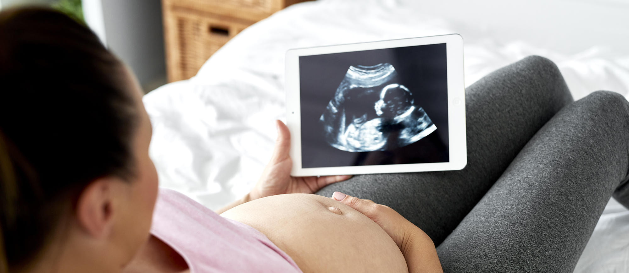 Pregnant woman watching at ultrasound record on tablet | Heart of a Child